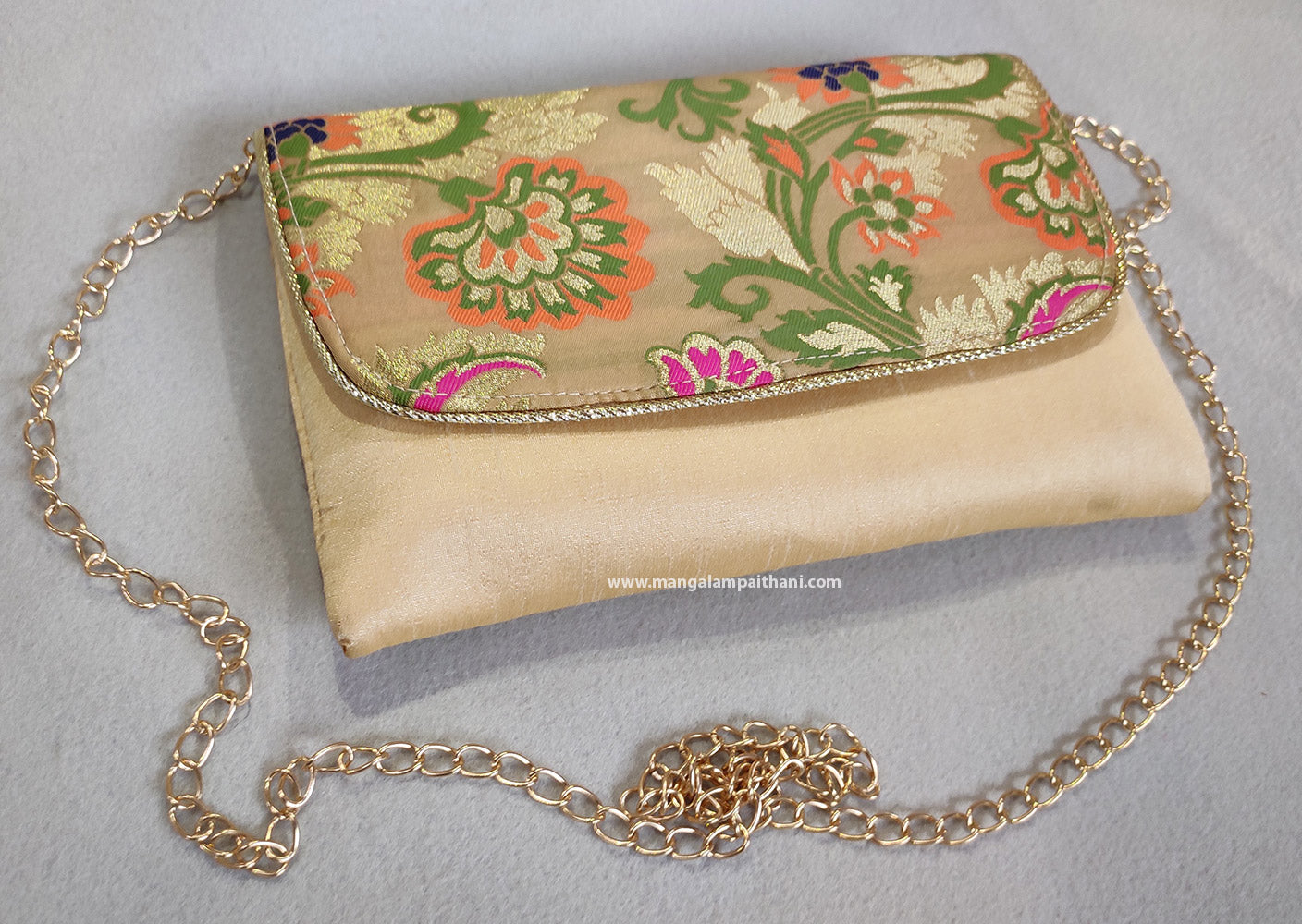 A clutch purse with a floral design and a detachable chain strap in gold color.