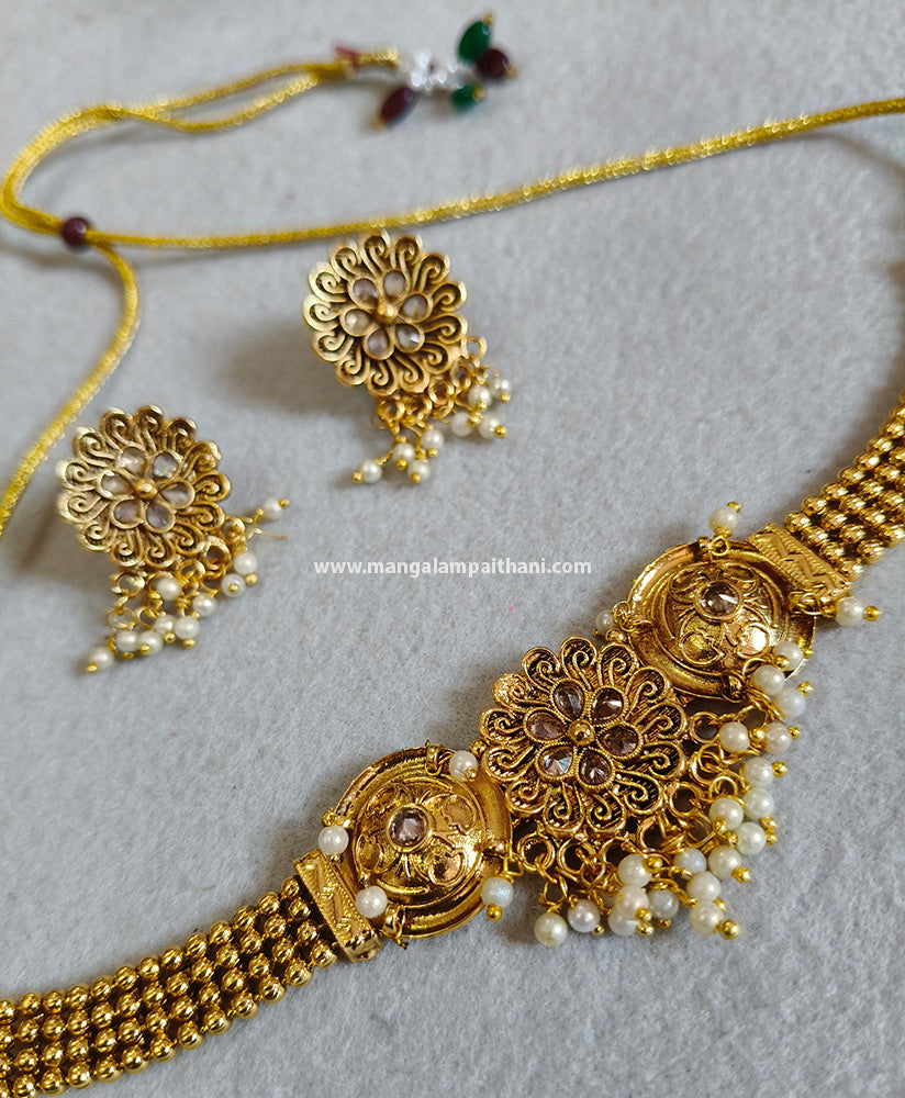 A gold-plated choker necklace set with a floral design and a pair of matching earrings