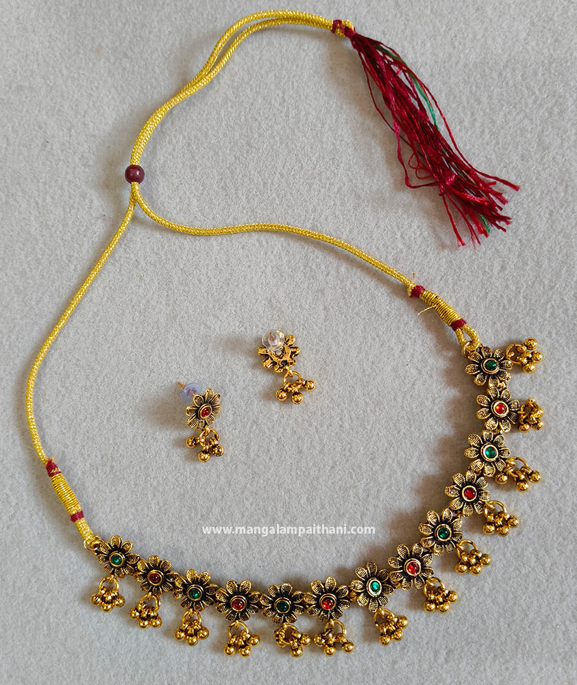 A gold-plated choker necklace with multicolored floral patterns and a pair of matching earrings.