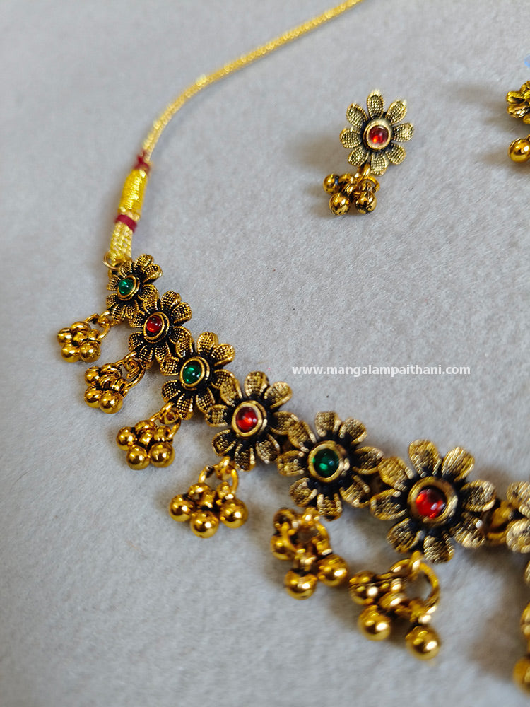 A gold-plated choker necklace with multicolored floral patterns and a pair of matching earrings.
