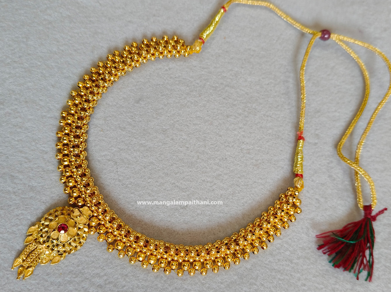 Gold plated choker necklace with a red and yellow design and a tassel at the end