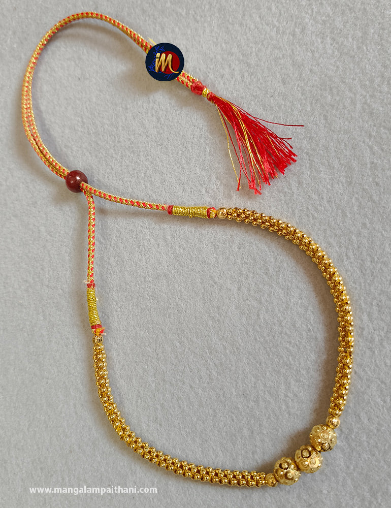 Gold plated choker necklace with a red and yellow design and a tassel at the end