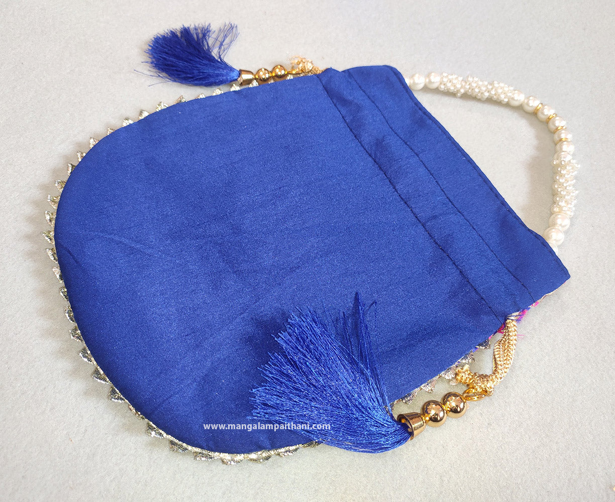 A multicolored designer women's clutch purse with floral patterns and a pearl handle