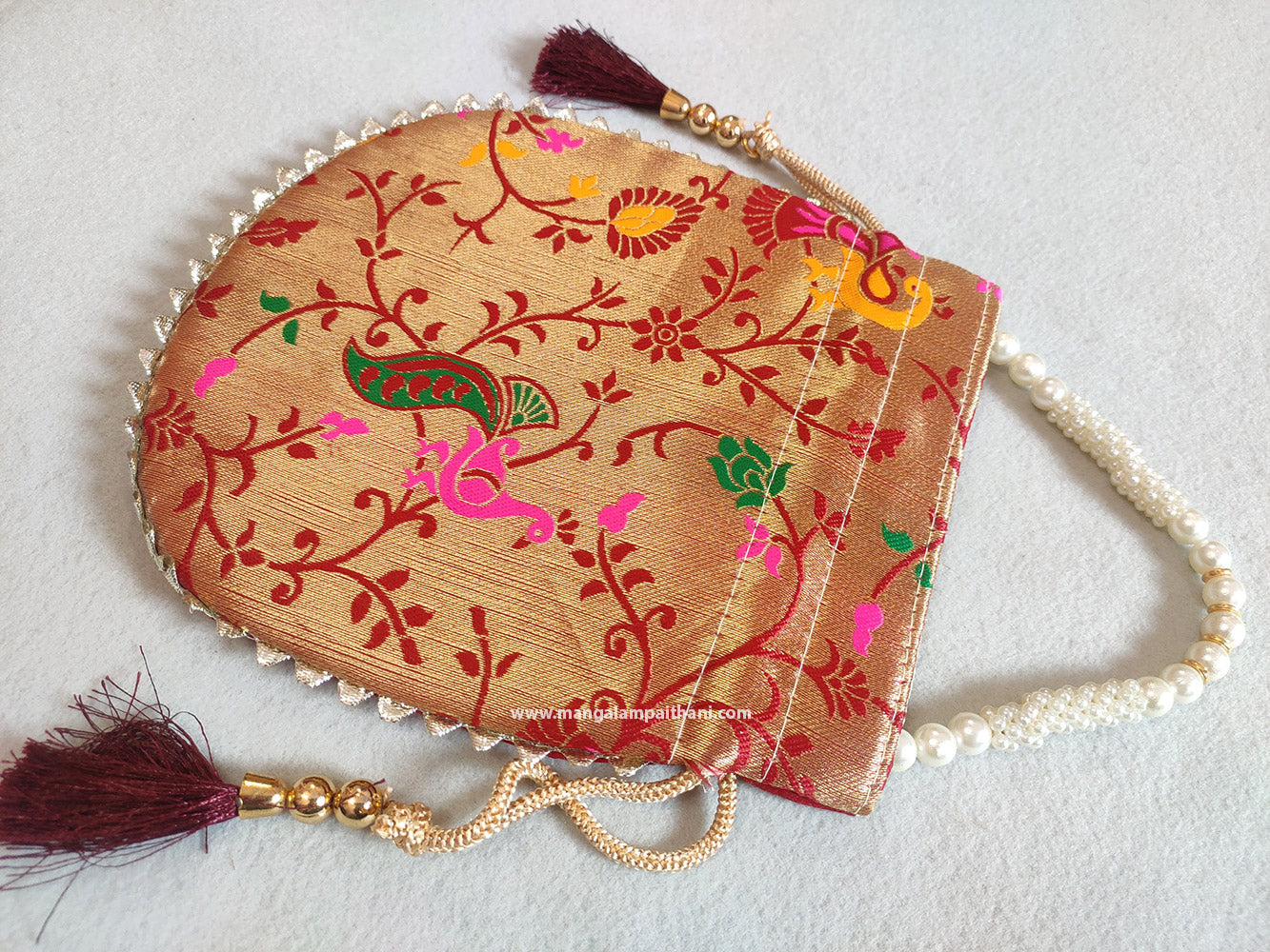 A multicolored designer women's clutch purse with floral patterns and a pearl handle